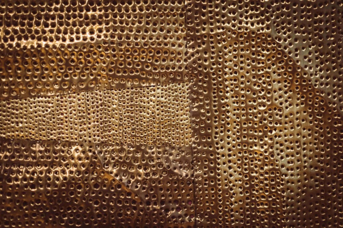 Close-up of hammered, perforated copper-toned metal